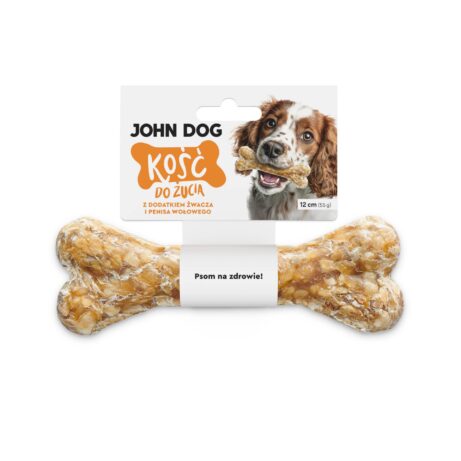 Kość do żucia 17 cm z dodatkiem żwacza i penisa wołowego w kolorze beżowym– widok od przodu. Na środku kości znajduje się biała owijka, do której przymocowana jest biała etykieta z pomarańczowym napisem. Po prawej na etykiecie jest pies rasy mieszanej, który trzyma kość w zębach.