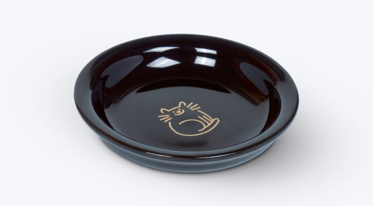 Czarny, ceramiczny talerz dla kota ze złotym rysunkiem kota na dnie.