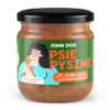 Karma mokra dla szczeniąt w słoiku z czarnym wieczkiem PSIE PYSZNE marki John Dog o smaku królika z dynią i ziemniakiem, na etykiecie widoczna jest kobieta w turkusowej bluzce którą liże w policzek mały piesek. Widok lekko z góry.