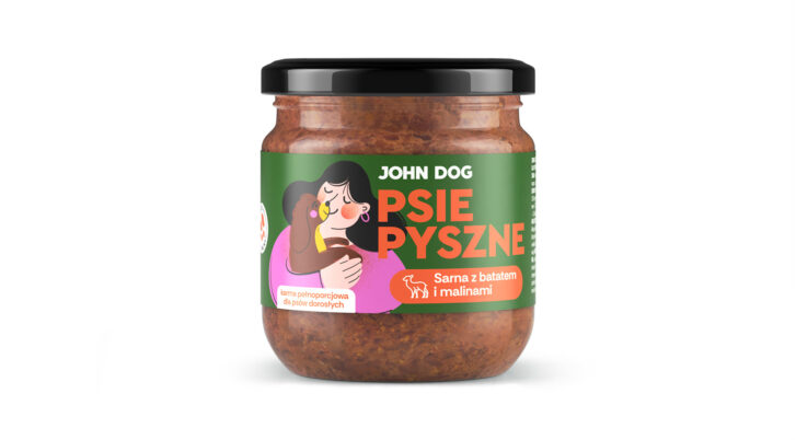 Karma mokra dla psów małych ras w słoiku z czarnym wieczkiem PSIE PYSZNE marki John Dog o smaku sarny z batatem i malinami, na etykiecie widoczna jest kobieta w różowej bluzce dająca buziaka brązowemu pieskowi. Widok od przodu.