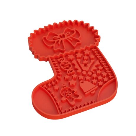 Mata do lizania w kształcie czerwonej świątecznej skarpety dla psa i kota, ozdobiona świątecznymi wzorami, takimi jak piernik, dzwonek i cukierek. Mata posiada różne wypustki, które służą do rozprowadzania pokarmu dla zwierząt.