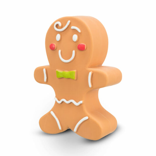 Zdjęcie pokazuje zabawkę dla psa w kształcie ludzika z piernika marki Trixie, wykonaną z lateksu, ozdobioną uśmiechem, guziczkami i kokardką.