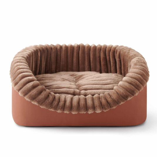 Pojedyncze brązowe, owalne legowisko dla psa z miękkim, żebrowanym pluszowym brzegiem i wyściełanym, teksturowanym wnętrzem.