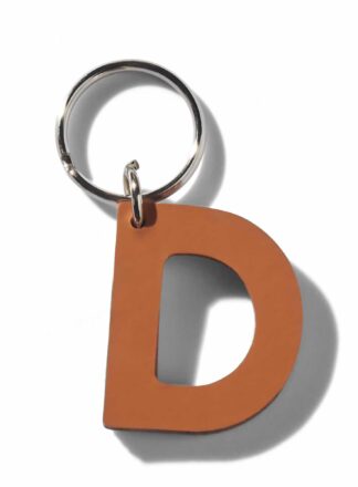 Brązowy, skórzany brelok do smyczy, szelek lub obroży w kształcie litery “D” z kolekcji MANIFEST marki John Dog. Brelok może być użyty jako inicjały imienia psa.