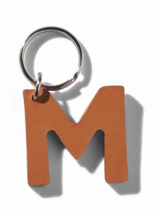 Brązowy, skórzany brelok do smyczy, szelek lub obroży w kształcie litery “M” z kolekcji MANIFEST marki John Dog. Brelok może być użyty jako inicjały imienia psa.