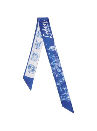 Cienka, dwustronna apaszka John Dog z kolekcji Lizbona w kolorze biało-granatowym ułożona na kształt odwróconej litery V. Z jednej strony są na niej rysunki granatowych portretów psów różnych ras na białym tle, a z drugiej rysunek białej panoramy miasta na granatowym tle.