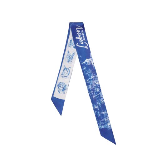 Cienka, dwustronna apaszka John Dog z kolekcji Lizbona w kolorze biało-granatowym ułożona na kształt odwróconej litery V. Z jednej strony są na niej rysunki granatowych portretów psów różnych ras na białym tle, a z drugiej rysunek białej panoramy miasta na granatowym tle.