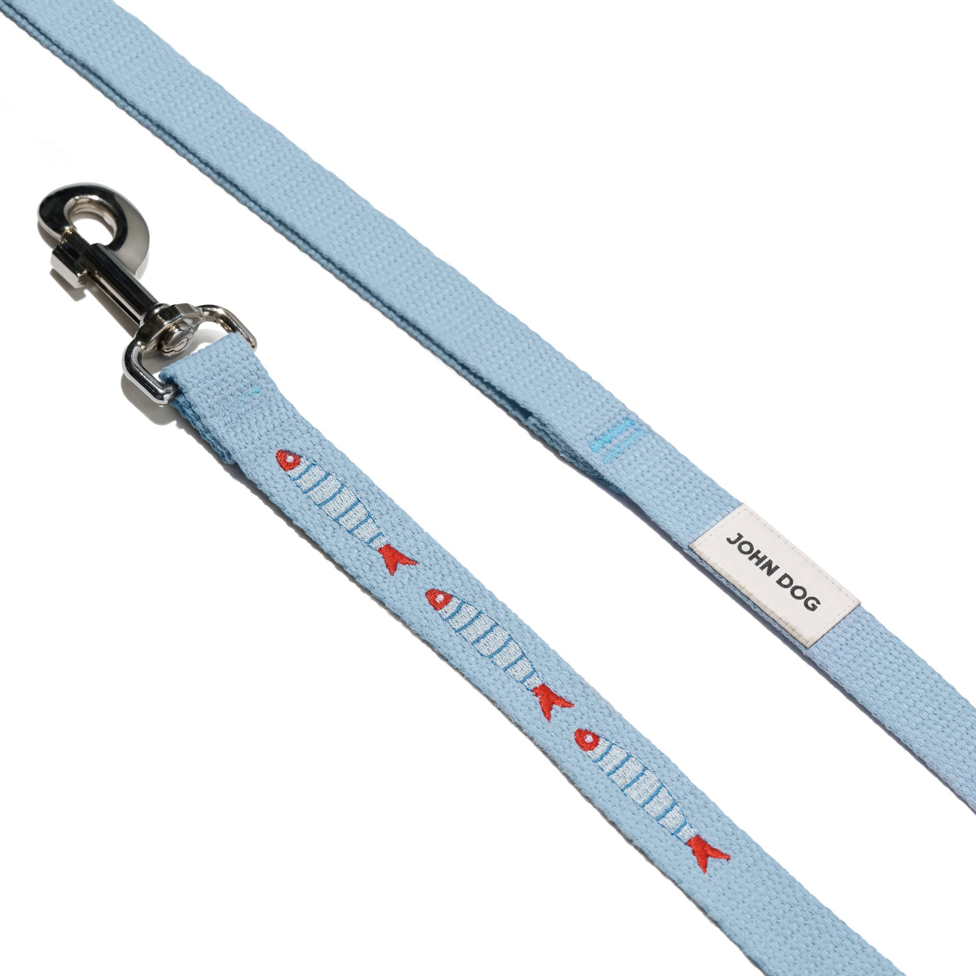 Zbliżenie na smycz prostą John Dog z kolekcji Lizbona w kolorze błękitnym z trzema haftami w kształcie rybek i beżowym logo. Smycz rozłożona na płasko.