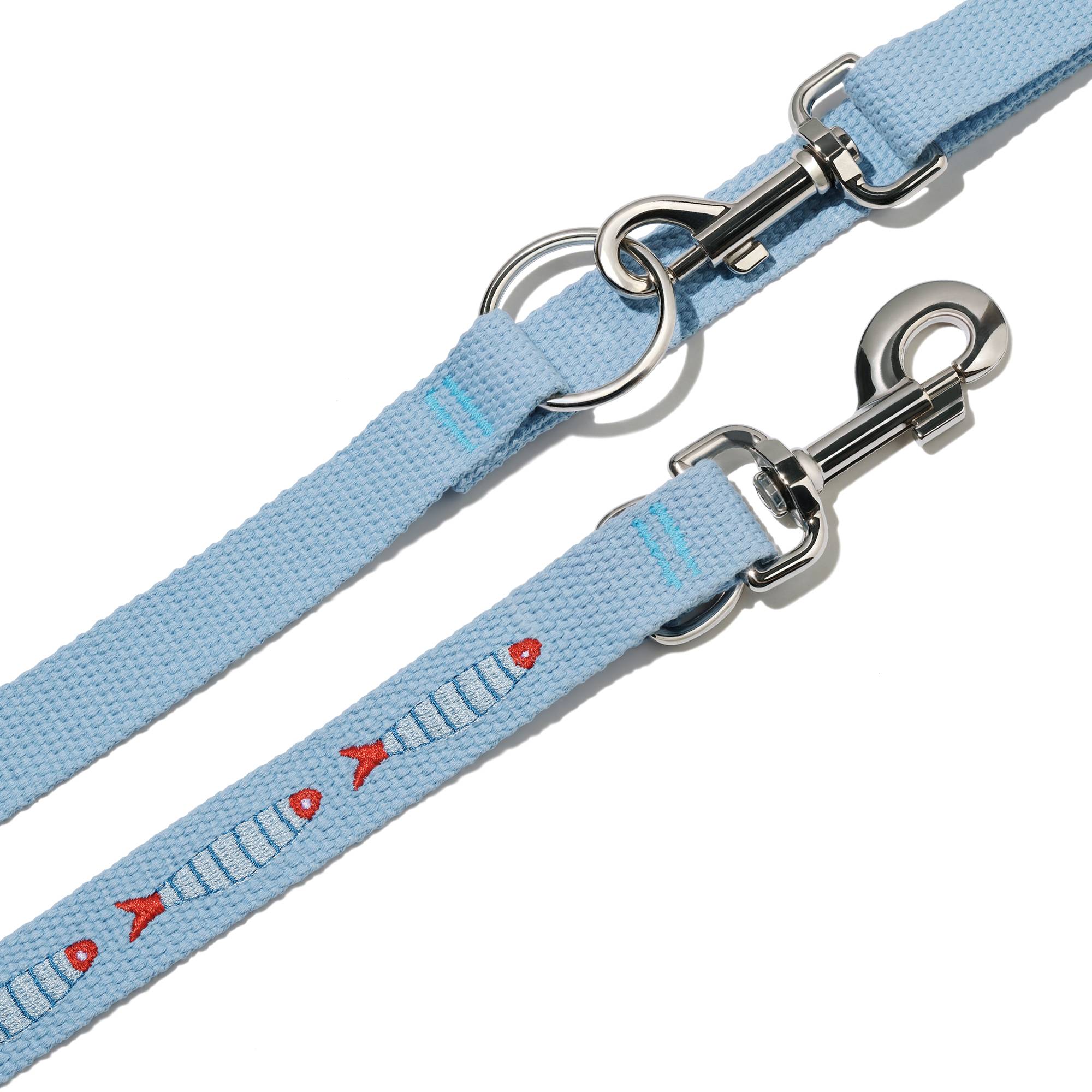 Zbliżenie na dwie taśmy smyczy przepinanej John Dog z kolekcji Lizbona w kolorze błękitnym z pinem w kształcie rybki.
