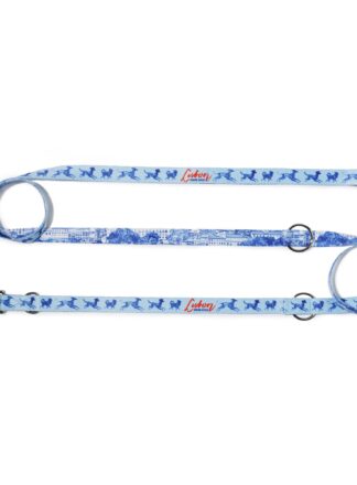 Smycz przepinana John Dog z kolekcji Lizbona we wzór z granatowymi psami i czerwonym napisem Lisbon po jednej stronie i rysunkiem panoramy miasta po drugiej stronie. Smycz rozłożona na płasko na kształt litery S, zawinięta po lewej i po prawej stronie w ślimak.