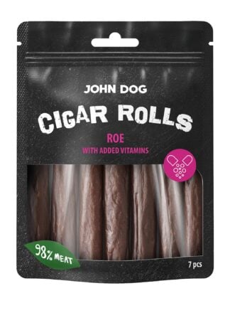 Przysmaki dla psa, siedem paluchów z sarny z dodatkiem witamin John Dog w czarnym opakowaniu z transparentną folią na środku przez którą widać produkt. Paluchy są w kolorze brązowym, na etykiecie jest umieszczony zielony listek z białym napisem oraz różowe kółko z ilustracją witamin, widok z przodu.