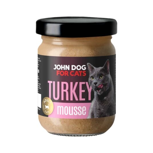 Słoik mokrej karmy z czarnym wieczkiem dla kotów John Dog for Cats o smaku indyka, w musie. Na ciemnej etykiecie widoczny jest szary kot i różowe napisy.