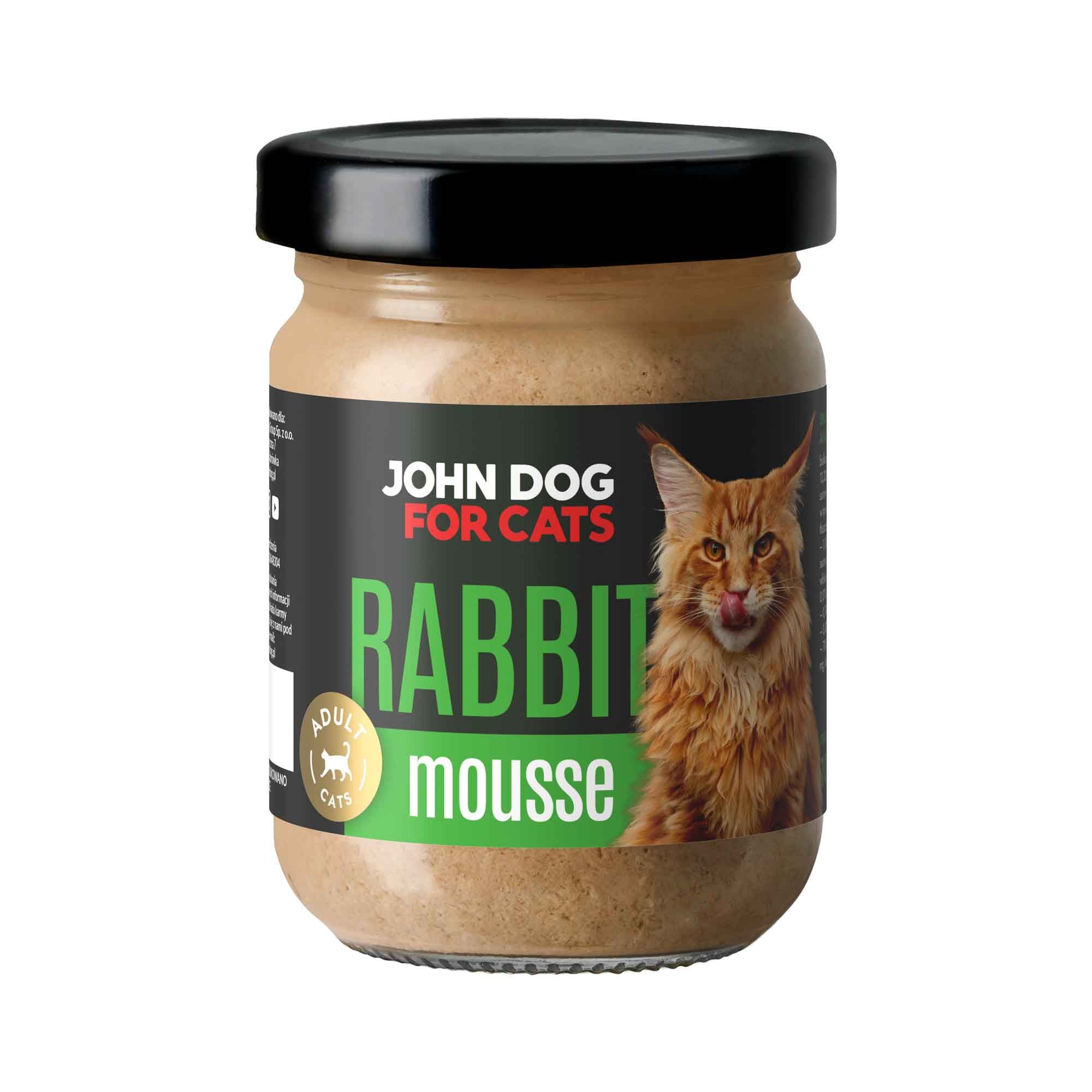 Słoik mokrej karmy z czarnym wieczkiem dla kotów John Dog for Cats o smaku królika, w musie. Na ciemnej etykiecie widoczny jest rudy puszysty kot i zielone napisy.