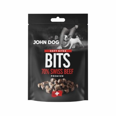 Czarne opakowanie przysmaków dla psów John Dog Bits Soft Bites Premium-kawałki zawierające 70% mięsa z wołowiny. Na opakowaniu znajduje się zdjęcie psa obok człowieka, grafika suszonych kostek mięsa oraz symbol szwajcarskiej flagi.