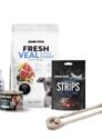 Na zdjęciu znajduje się zestaw produktów i akcesoriów John Dog dla szczeniaka: sucha karma FRESH cielęcina z królikiem Happy Start, mokra karma Pure Black indyk oraz przysmaki Soft Bites Strips 95% szwajcarska jagnięcina. Zestaw uzupełniają olej rybny VetFerus Golden Omega-3 oraz beżowa smycz John Dog z kolekcji manifest.